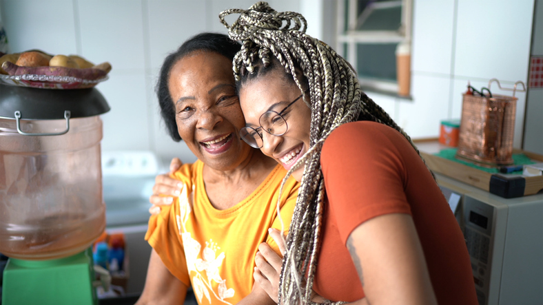 Portrait of grandmother and granddaughter embracing at home