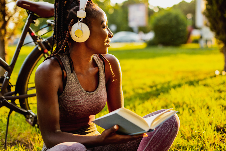 Young African American woman is reading a book in nature