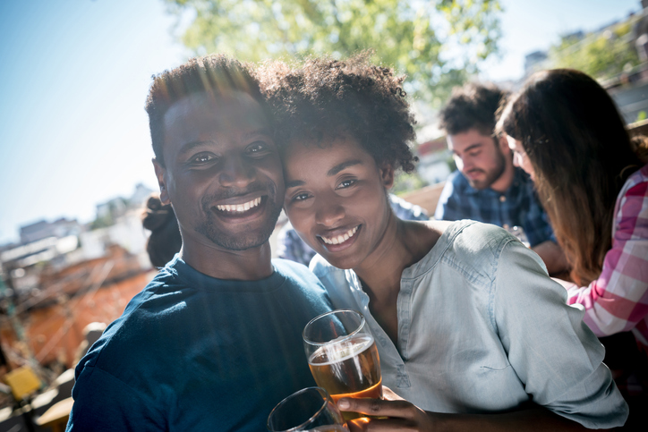 Portrait of a beautiful black couple on a date enjoying a beer at an outdoor bar