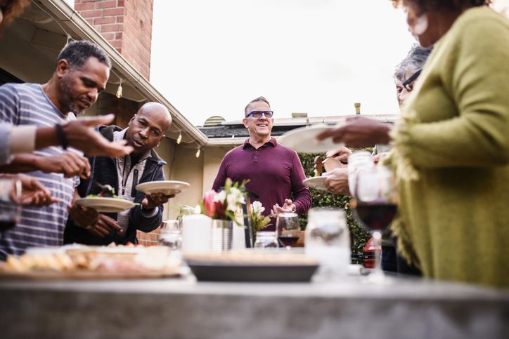 Mature friends gather around dinner table at party