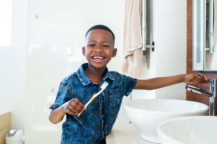 Young Boy brushing his teeth smiling