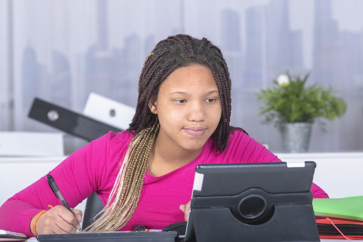 Teenage Girl With Braided Hair Studying On Table At Home