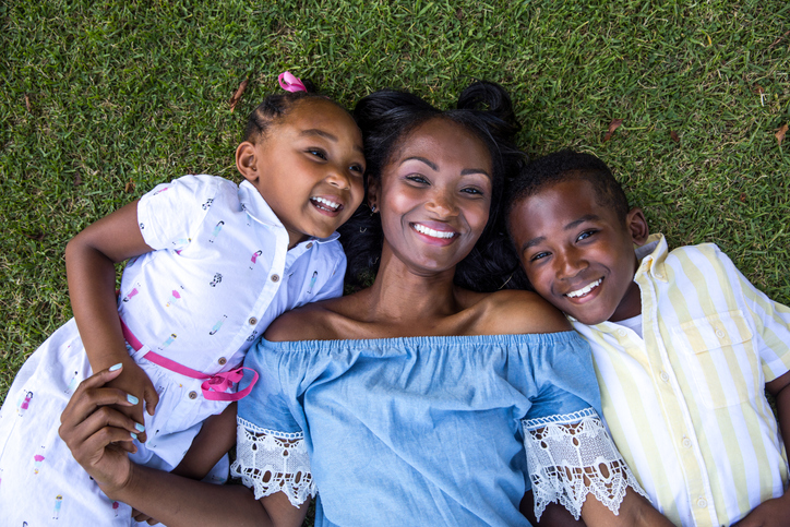 Young african-american family resting lying down on the grass