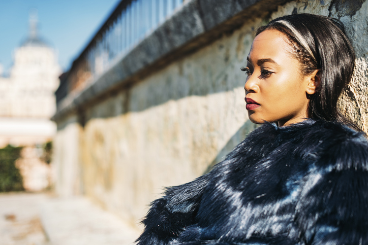 Thoughtful young woman leaning on wall