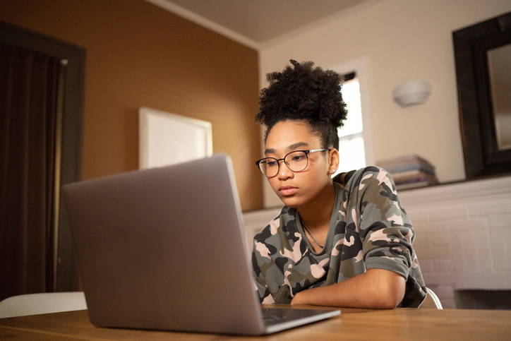 Natural Beautiful Teenage African American Girl Studying Online at Home Using a Laptop