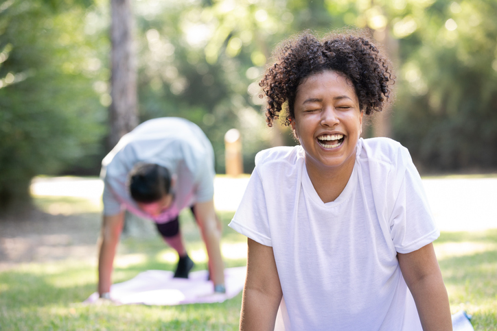 Man and woman laughing while doing yoga outdoors