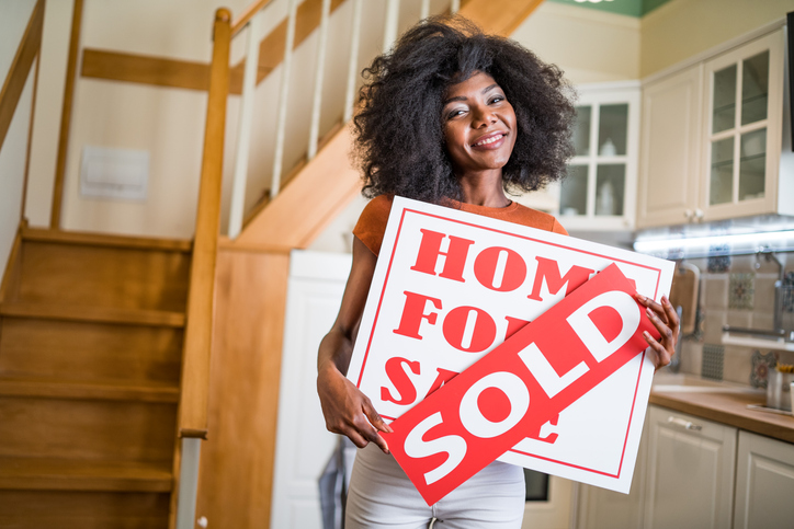 Smiling african woman holding sign for sale and sold