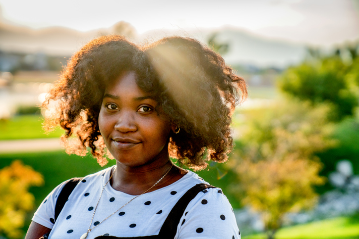 Beautiful Caribbean African Woman Smiling at the Camera Backlit by Beautiful Sunset Lighting with Lens Flare