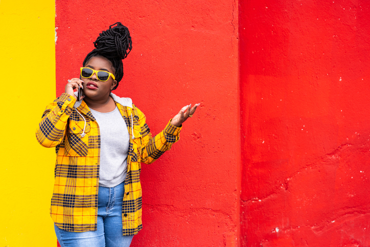 Afro woman on red background talking on a smartphone