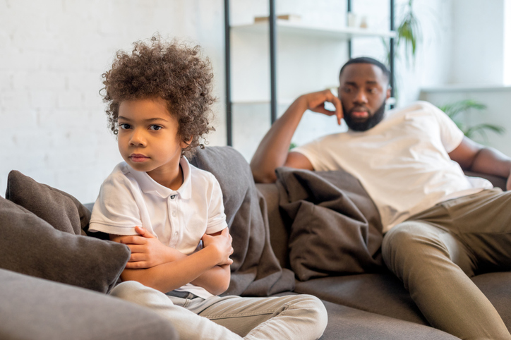 Upset child sitting and turned away from father