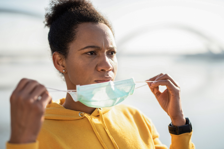 Sporty woman putting a protective face mask on.