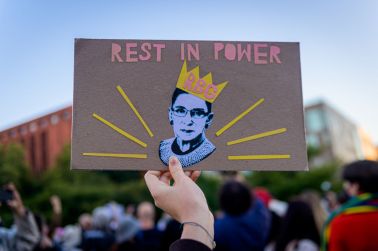 A participant holding a sign at the RBG memorial. A crowd on...