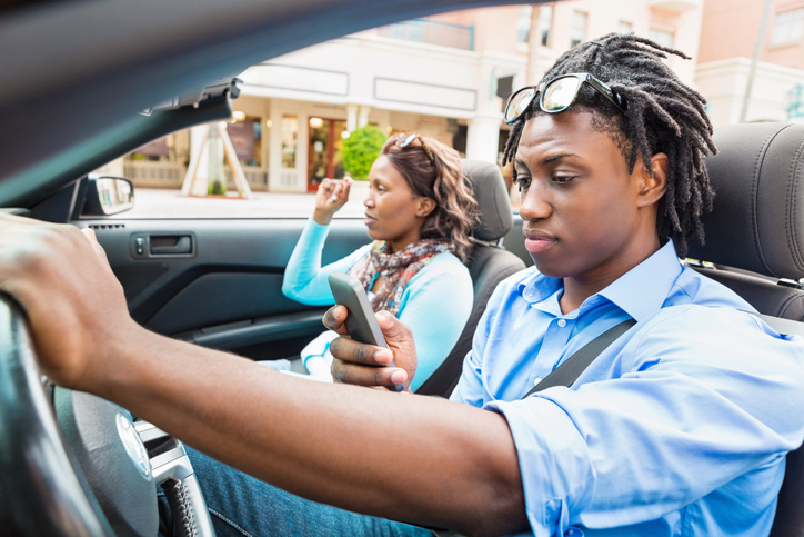 Young man dangerously looking down at cell phone while driving