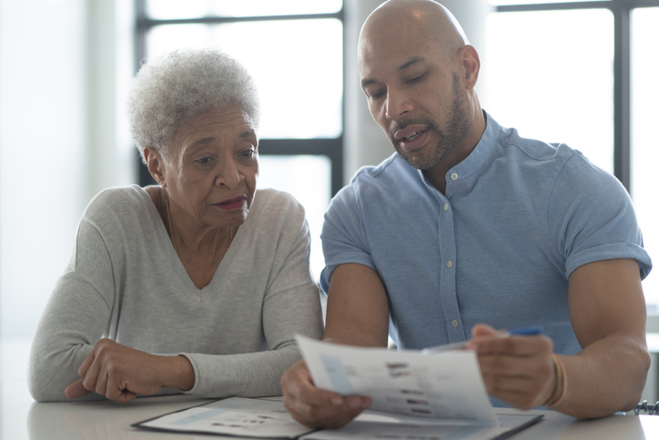 A Male African American Adviser Meets with A Female Senior Client stock photo