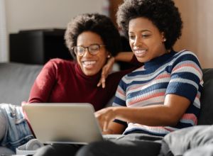 Two Black twin sisters spending time using laptop together at home