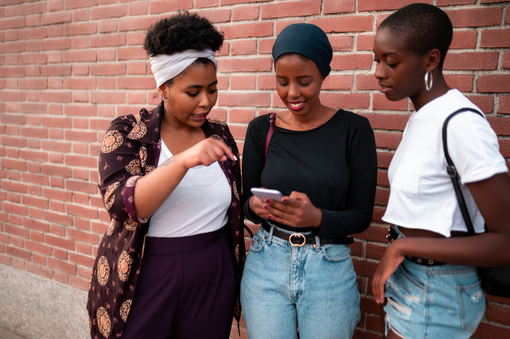 Three female friends standing and looking at the phone