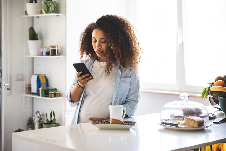 Young pregnant woman in the kitchen drinking a coffee cup in the morning