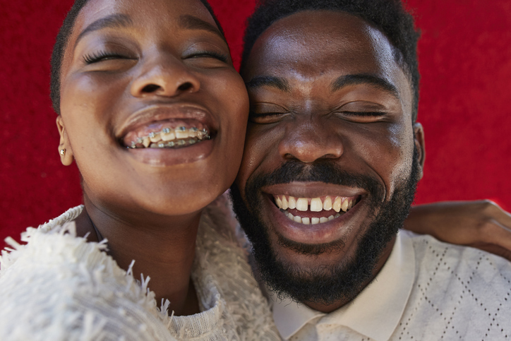 Smiling friends with eyes closed against red wall