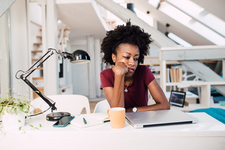 African-American woman sitting at her home office, bored of working