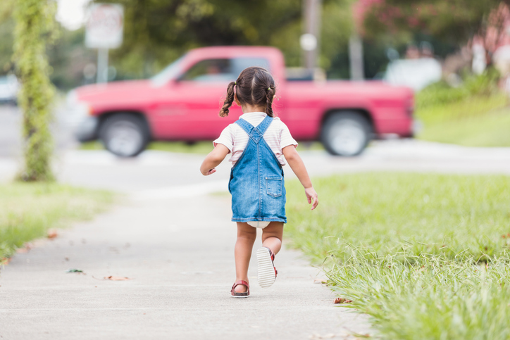 Rearview photo preschool girl running down sidewalk