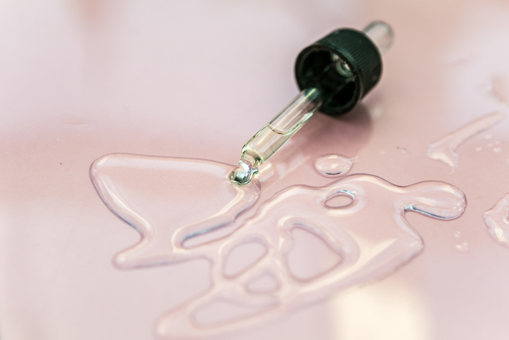 Liquid gel or serum drop on pastel background in macro. Flat lay style.