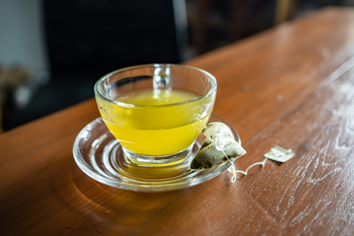 A cup of green tea with tea bag on the table