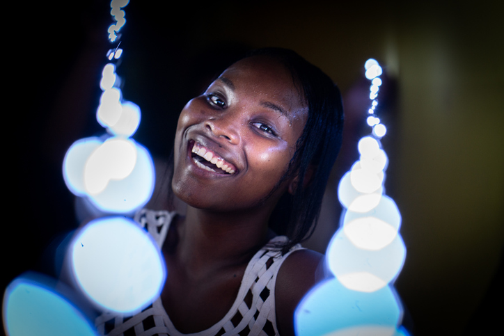 Happy young black woman partying in club with lights around