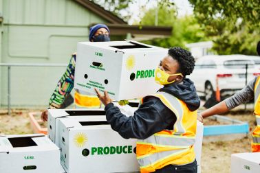 Volunteer stacking CSA boxes while working at community center