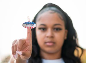 Young woman holds up "I voted" sticker