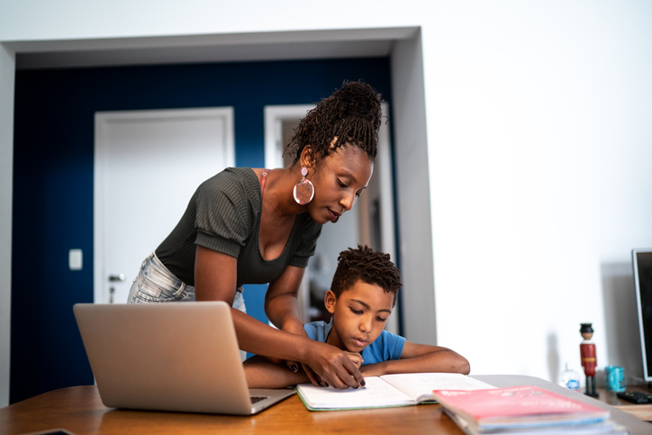 Mother helping son doing homework using laptop on homeschooling