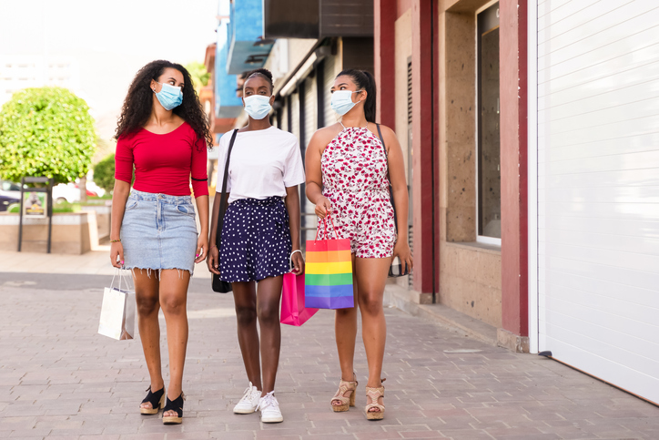 Friendship shopping with protective masks for coronavirus. A picture of girls with shop bags, closed shops. Shopping, tourism and virus concept.