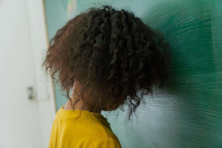 School girl resting head on blackboard