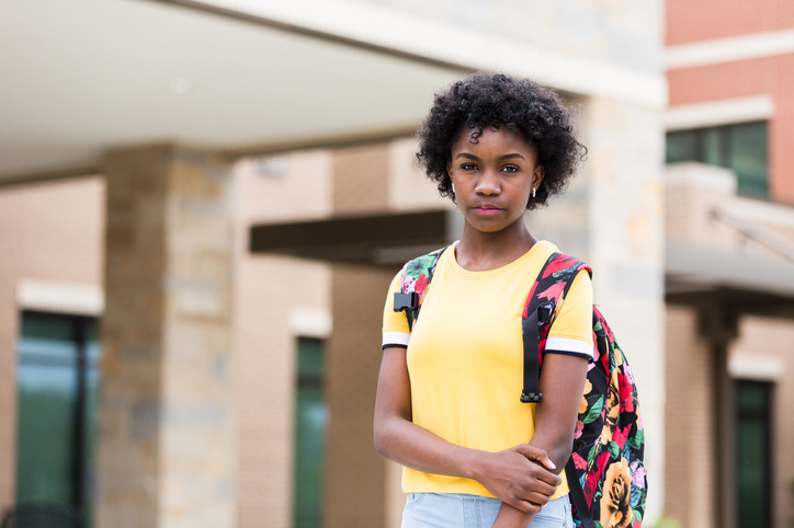 Angry, possibly anxious, tween girl in front of school building