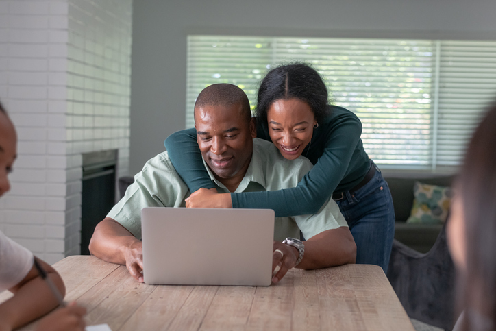 Black father and teenage daughter use video chat to visit with family and friends