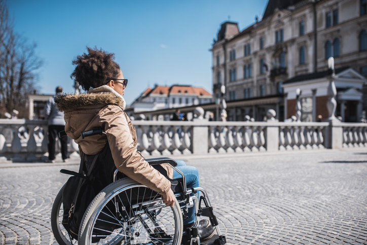 Disabled woman in a wheelchair enjoying the sun in the city