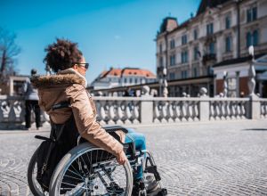Disabled woman in a wheelchair enjoying the sun in the city