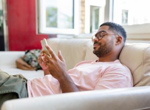 Relaxed man sitting on sofa using cell phone