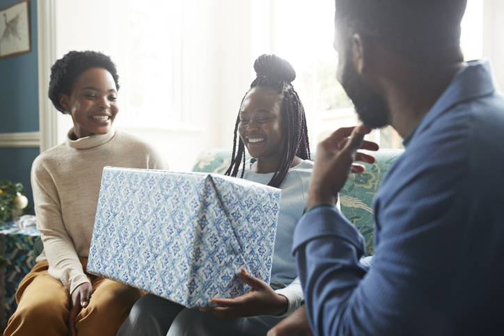 Family looking at teenage girl holding gift box