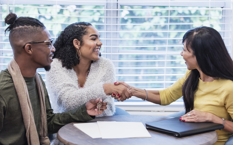 Young couple completing deal with realtor, handshake