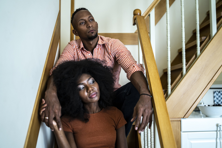 Young afro couple sitting on the steps in their home