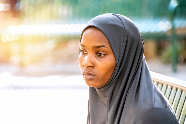 Pensive serious young black muslim woman wearing a hijab looking away