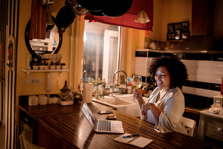 Black woman having a video call while enjoying a glass of red wine