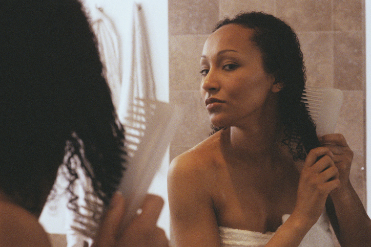 Woman in Bathroom Combing Hair