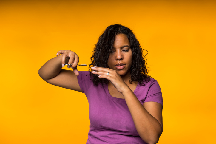 Woman Cutting Her Hair Over Orange Background