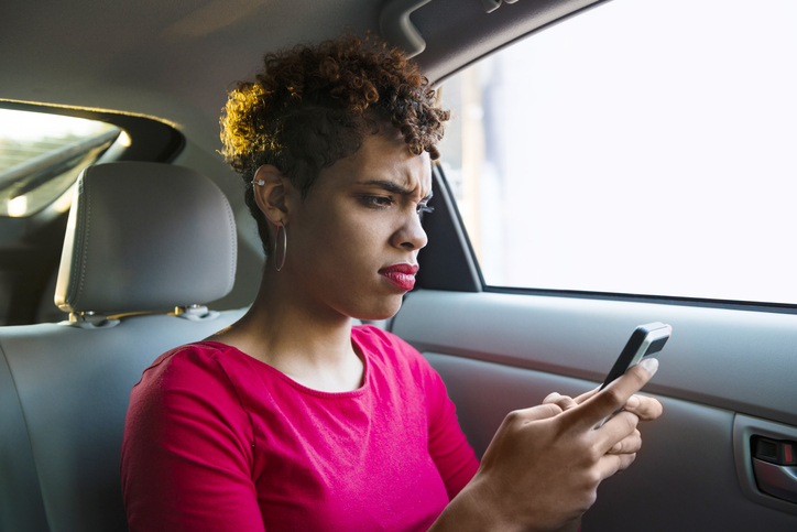 Annoyed Millennial Passenger Makes a Face while Texting in Backseat
