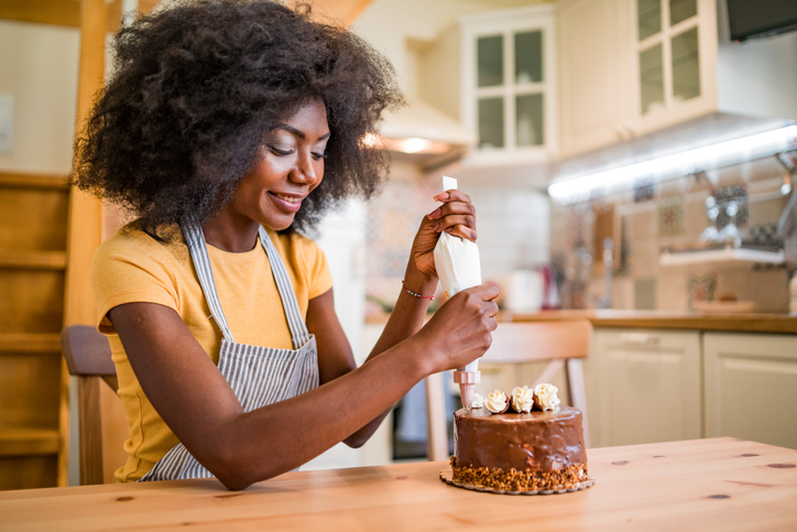 Afro women decorating a cake at home