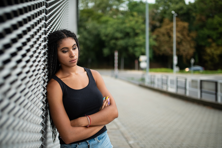 Unhappy teen girl leaning on mesh frame