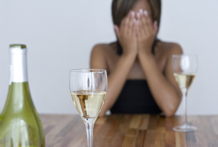Woman sitting at table with wine glasses and wine