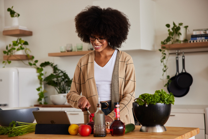 Smiling young woman preparing a meal from a recipe online
