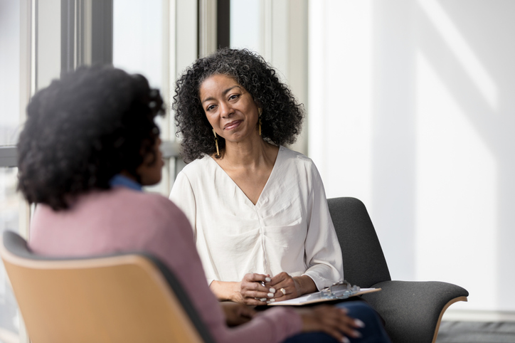 Mature counselor listens compassionately to unrecognizable female client